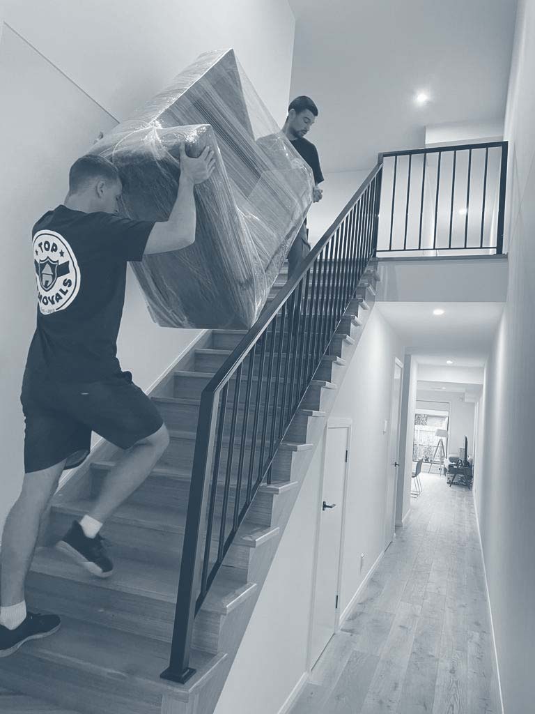 Removalists carrying a sofa up the stairs